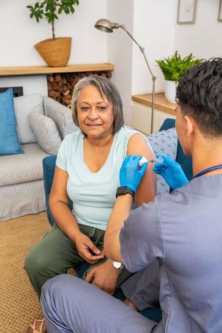 Elderly Woman Receiving Vaccine from Male Nurse at Home