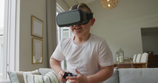 Smiling caucasian boy standing in living room and using vr headset at home. spending time alone at home.