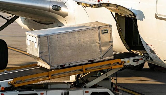 Aluminum cargo container being loaded into aircraft belly compartment on belt loader