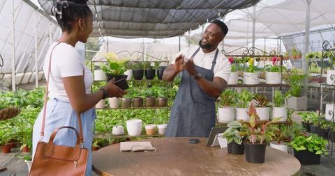 African American Vendor and Customer Discussing Potted Plants in Greenhouse