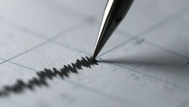 Macro pen tracing seismic waveform on graph paper closeup showing signal readout precision