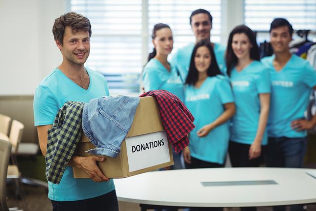 Portrait of volunteer holding clothes in donation box at workshop