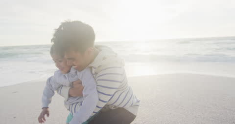 Father and Daughter Smiling and Hugging on Sunny Beach
