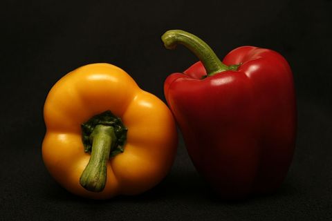 Vibrant red and yellow bell peppers on dark background, fresh capsicum close-up