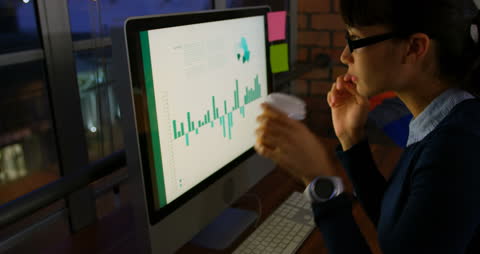 Businesswoman Analyzing Data on Computer Screen at Night