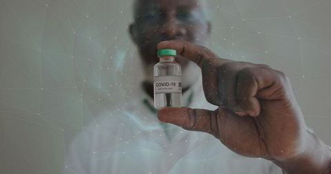 Doctor holding covid-19 vaccine vial with green cap closeup for healthcare and research