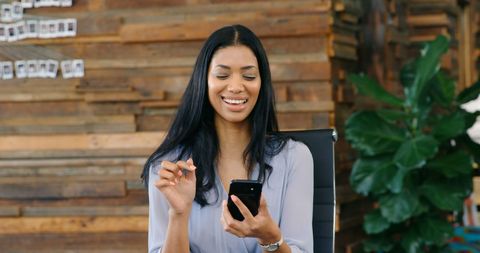Relaxed woman enjoying mobile break in stylish office environment