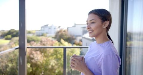 Smiling Woman Relaxing with Morning Coffee on Home Balcony