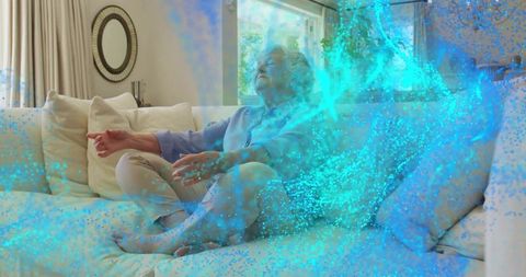 Senior woman relaxing on sofa as glowing blue particles swirl for meditation visualization