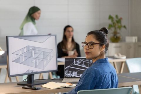 Asian architect reviewing 3d floor plan at open-plan studio for collaborative design