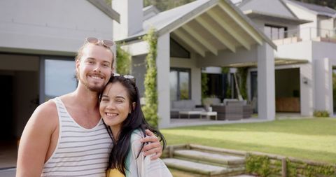 Happy Young Couple Embracing Outside Modern Poolside Home