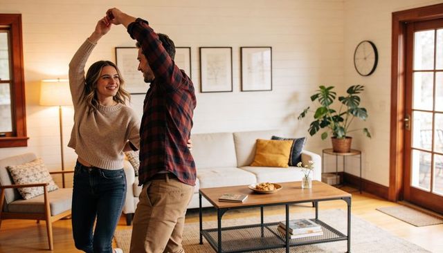 Young couple dancing in cozy rustic living room embracing warm home romance moment