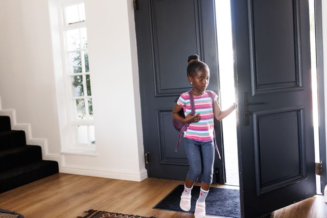 African american girl coming home from school, opening front door, with copy space. Childhood and domestic life concept.