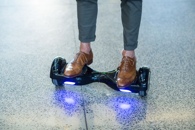 Businessman in brown leather shoes riding a hoverboard on a polished office floor. Ideal for illustrating modern office environments, innovative transportation methods, or casual business attire. Can be used in articles about workplace trends, technology in business, or personal transportation devices.