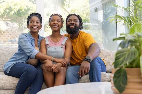 Sunlit african american family sharing warm moment on modern sofa with indoor plants