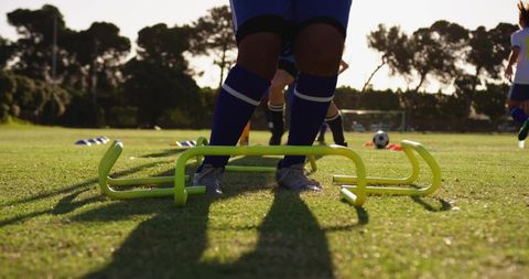 Youth Soccer Player Clearing Agility Hurdles During Outdoor Training Drill on Grass Pitch