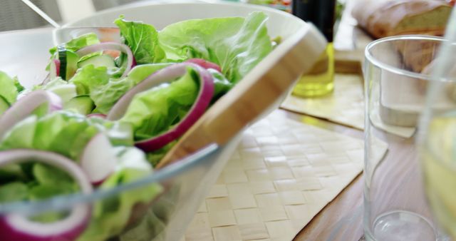 A fresh salad with crisp lettuce and sliced onions is presented on a table, with copy space. It's a healthy meal option, indicative of a nutritious and balanced diet.