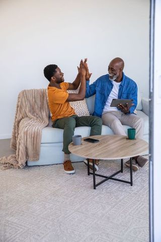 African American Father and Son Bonding at Home with Tablet and Mugs
