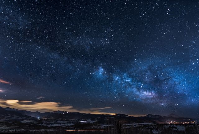 Milky Way arching over mountains at night. Perfect for use in astronomical studies, nature backgrounds, desktop wallpapers, or travel and adventure promotions.