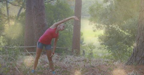 Woman in Sportswear Stretching in Forest Clearing