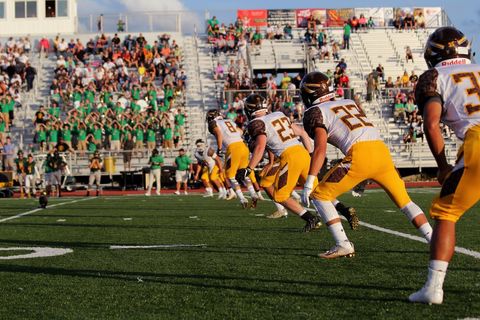 High School Football Team Lining Up Kickoff With Crowd Cheering in Sunny Stadium Friday Night