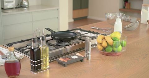 Modern kitchen island with stainless gas cooktop and frying pan, citrus bowl on countertop