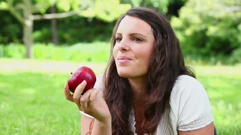 Woman Enjoying a Red Apple in Park