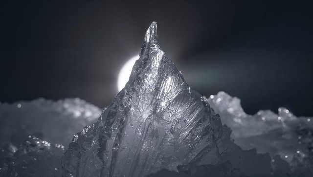 Moonlit ice peak glowing with crystalline facets on frozen landscape
