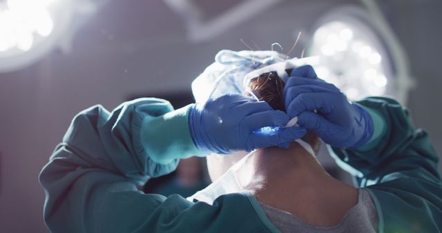 Image of rear view of asian female surgeon tying face mask in operating theatre. Hospital, medical and healthcare services.