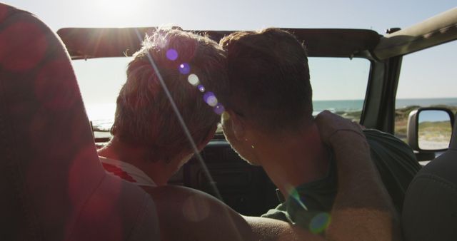 Happy caucasian gay male couple sitting in car and embracing on sunny day at the beach. summer road trip and holiday in nature.