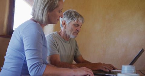 Senior couple engaged with laptop technology at home table