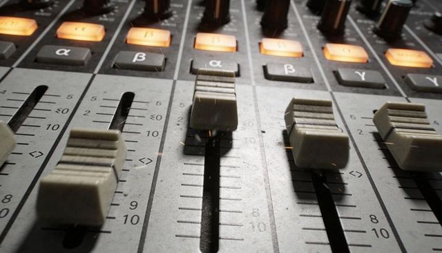 Central channel fader showing grooved caps and backlit buttons on mixing console