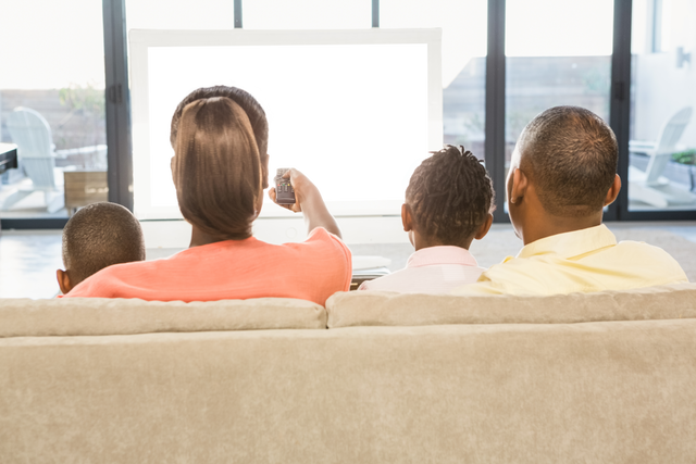 Over Shoulder View of Family Watching TV in Transparent Living Room Setting - Download Free Stock Videos Pikwizard.com