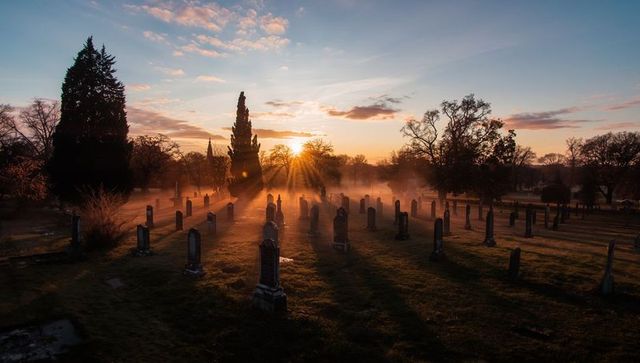 Golden sunrise illuminating mystical foggy cemetery