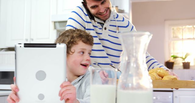 Father Multitasking with Phone and Serving Breakfast While Child Uses Tablet - Download Free Stock Images Pikwizard.com