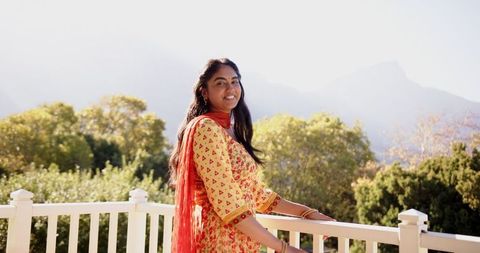 Woman Enjoying Scenic Mountain View from Balcony in Traditional Attire