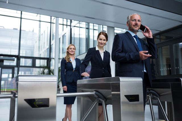 Business professionals scanning their access cards at a turnstile gate in a modern office building. Ideal for illustrating corporate security measures, access control systems, professional environments, and teamwork in business settings.