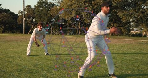 Cricket fielder sprinting with teammate crouching and data network overlay on grassy park