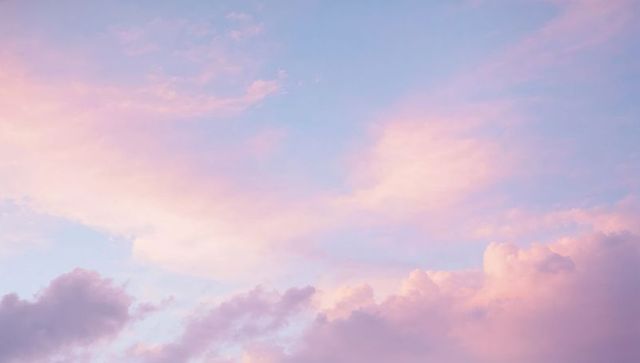 Pastel dawn clouds drifting over serene blue sky with soft pink and lavender gradient