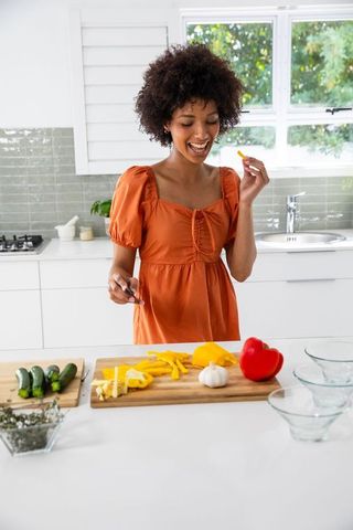 Smiling Woman Slicing Vegetables in Modern Kitchen