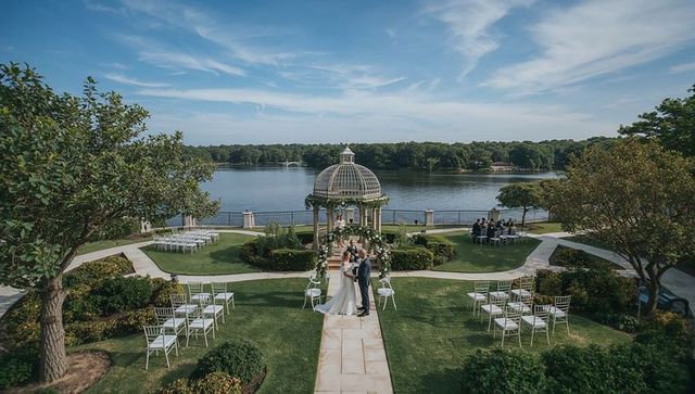 Lakeside wedding beneath floral gazebo overlooking tranquil lake and garden lawn