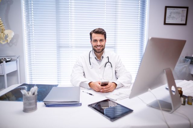 Portrait of male doctor sitting at desk - Download Free Stock Photos Pikwizard.com