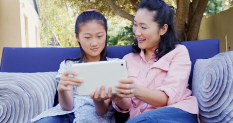 Mother and daughter using tablet, outdoor family bonding time
