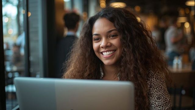 Happy Woman Using Laptop at Cozy Cafe Table