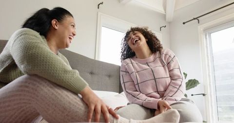 Diverse Friends Laughing and Relaxing on Bed in Bright Cozy Bedroom