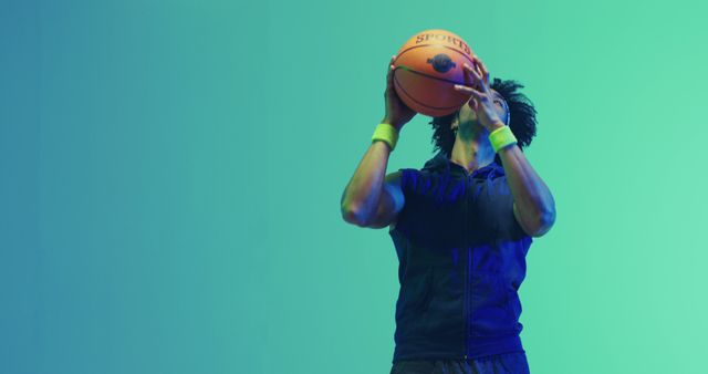 Young male basketball player in action, preparing to shoot a ball. Useful for sports-related content, athletic advertisement, fitness inspiration, youth programs promotion, and basketball training materials.