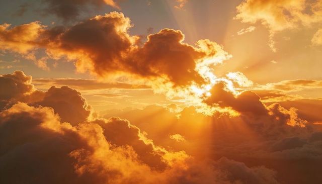 Golden sunset sky with glowing cumulus and crepuscular rays breaking through clouds