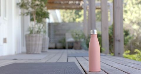 Stainless steel pink water bottle under pergola with yoga mat
