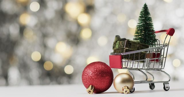 Portraying a miniature shopping cart filled with small Christmas decorations, including a red glitter bauble, a golden bauble, and small gift boxes. Perfect for use in promotional and marketing materials related to holiday sales, festive advertisements, seasonal celebrations, and gift inspiration.