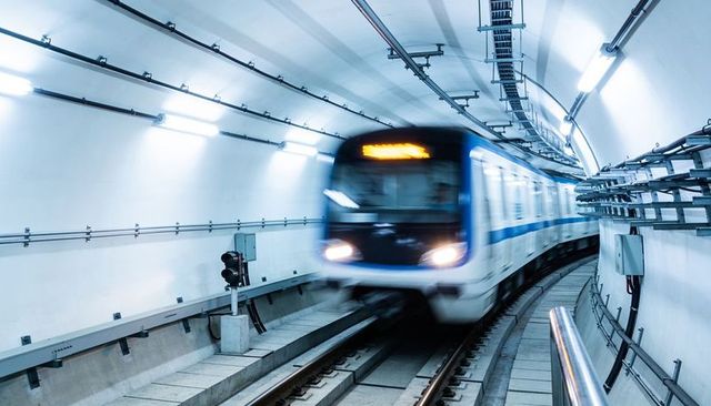High-speed metro train racing through curved illuminated subway tunnel with motion blur